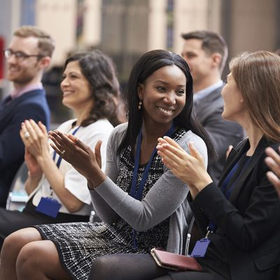 Young training solution professionals applauding at an event.