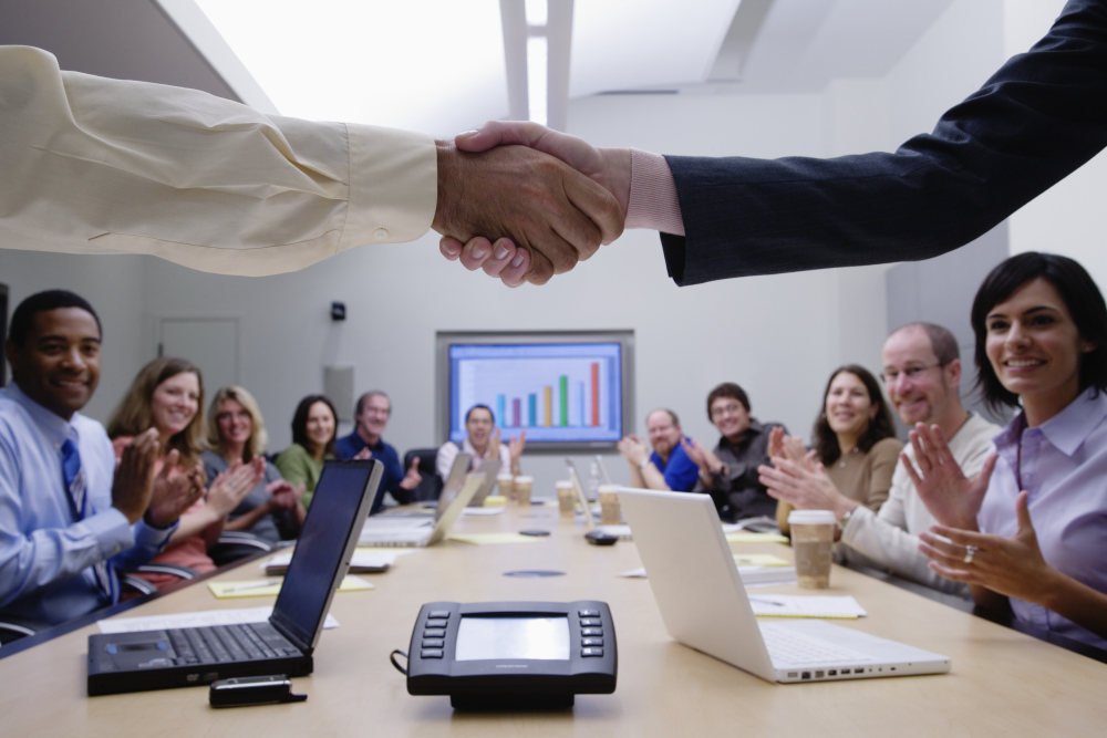 Business consulting service professionals shaking hands with people clapping